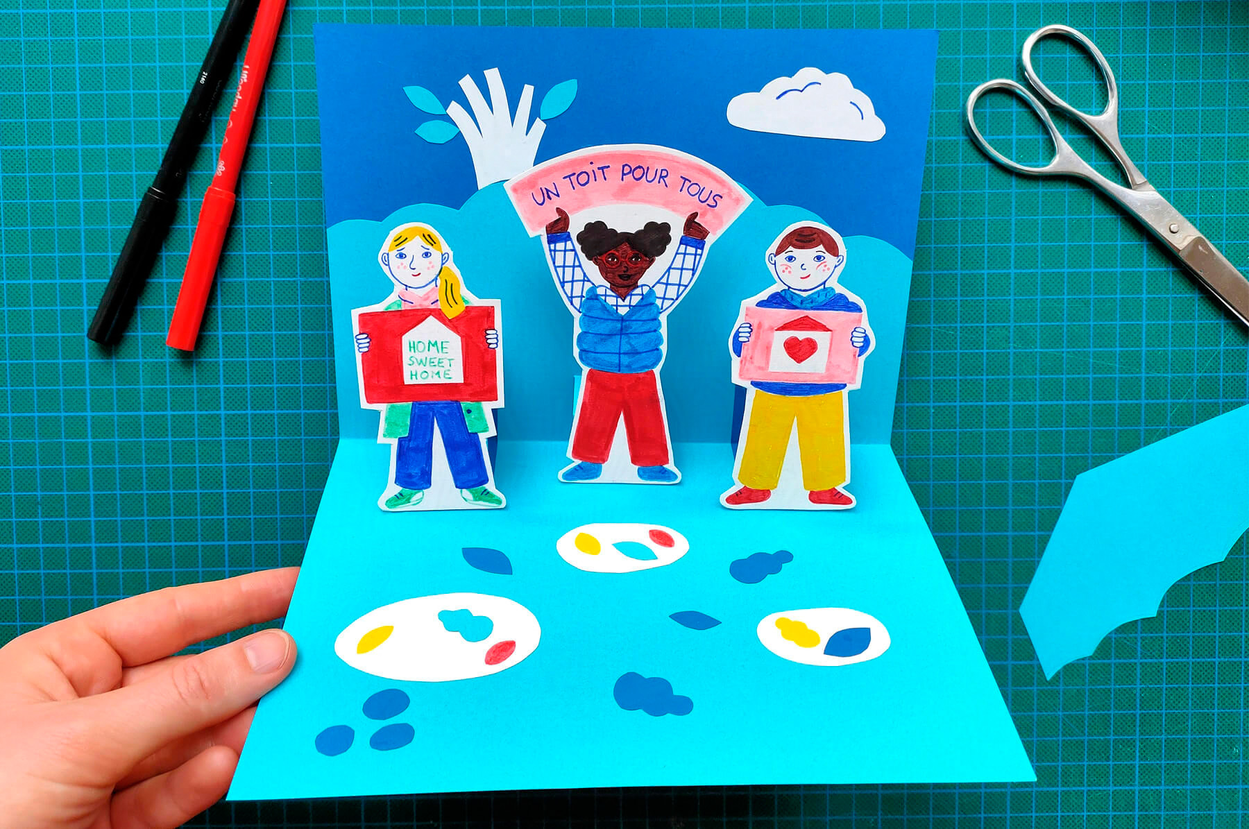 atelier créatif de carte pop-up pour les enfants avec du papier découpé et des feutres en lien avec le roman jeunesse Un toit pour tous