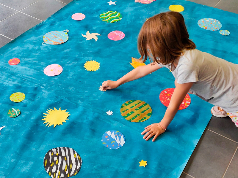 scène d'atelier artistique de création d'une fresque sur le thème de l'espace pour les enfants