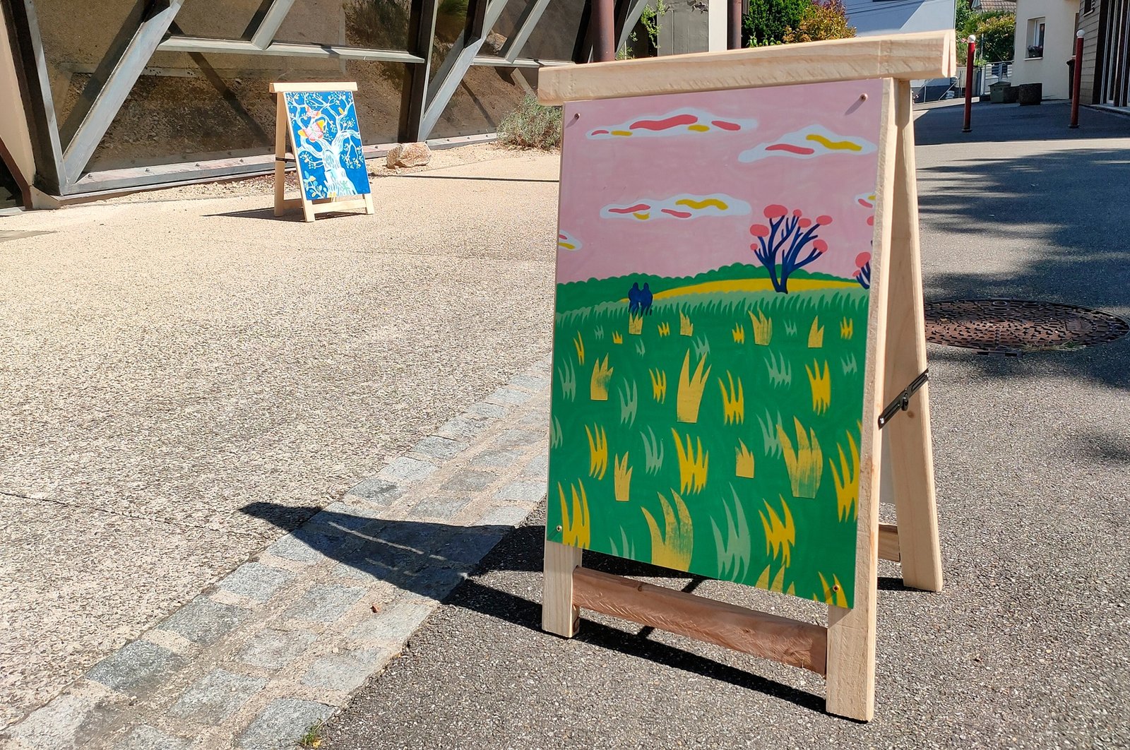 panneau d'exposition de peinture en extérieur représentant un paysage avec des silhouettes